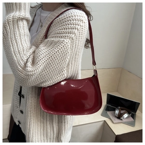 Macro shot of glossy deep red patent leather baguette bag under daily office scene