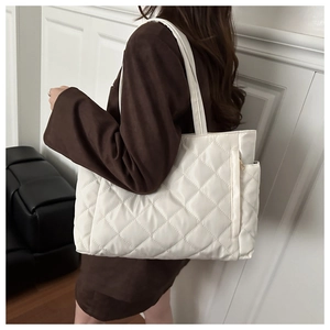 Detailed view of white quilted puffer shoulder bag with side zipper pocket on a model