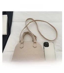 Mini beige shell bag with crocodile texture and phone size comparison on white fabric