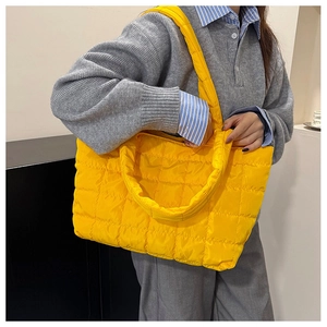 Close-up of vibrant yellow quilted nylon tote bag with puffer texture and wide shoulder strap