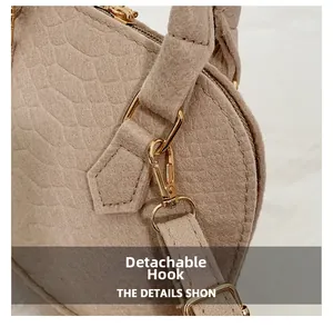 Detail of beige faux crocodile texture and shiny gold detachable metal strap hooks