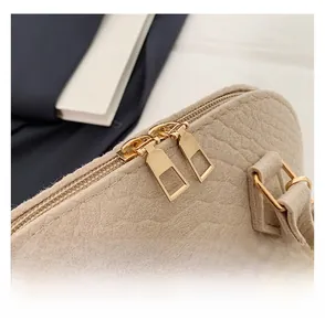 Macro shot of smooth gold-tone dual zippers on a beige faux-crocodile leather handbag