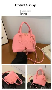 Detailed views of a pink crocodile-embossed shell bag with top handles and gold hardware