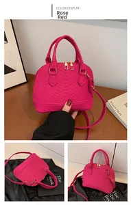 Detail view of rose red shell bag featuring crocodile texture and golden hardware