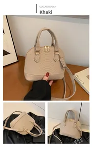 Detail of khaki shell-shaped bag with faux crocodile texture and gold hardware zipper