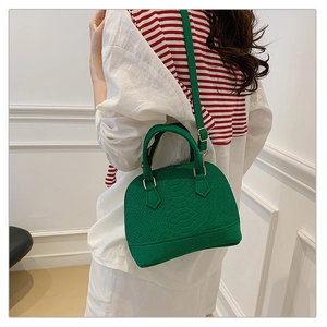 Detail of green faux crocodile skin shell bag with adjustable shoulder strap and gold hardware