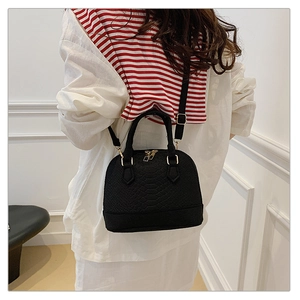 Detail of black shell crossbody bag with snake texture and gold metal hardware