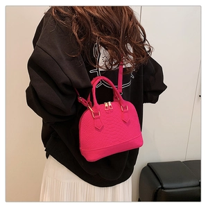 Detail of rose pink crocodile embossed shell bag shown on model with gold hardware