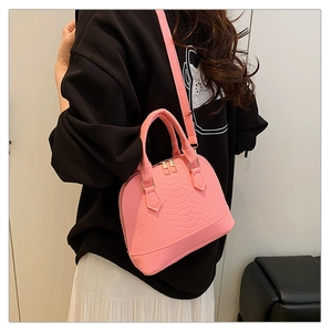 Detailed view of pink croc-textured shell bag worn by model with adjustable strap