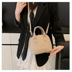 Detail of beige crocodile pattern shell bag showing texture and crossbody strap