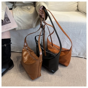 Detail of minimalist leather shoulder bags in dark brown and black with top zippers