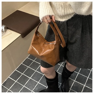Dettaglio della borsa hobo color caramello con texture in finta pelle e tracolla minimalista