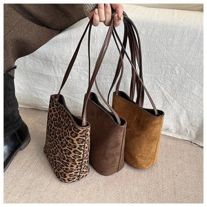Dettaglio di eleganti mini borse a secchiello in pelle scamosciata leopardata e caffè