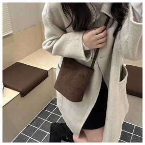 Dettaglio di una borsa a secchiello vintage in pelle scamosciata marrone con cappotto