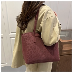 Leopard print burgundy tote bag shown from a side-view angle on woman shoulder