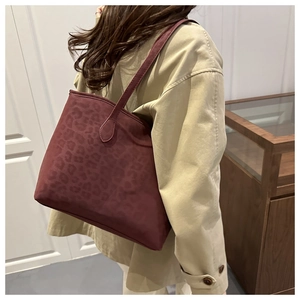 Side view of large burgundy leopard print tote bag worn with a beige trench coat