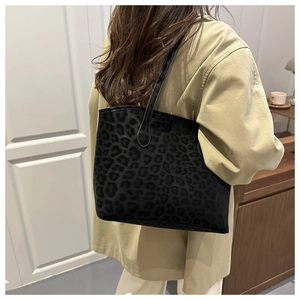 Detail of black leopard print tote bag texture and slim shoulder strap on model