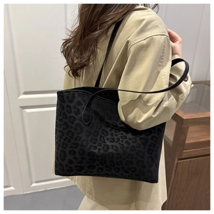 Detail view of large leopard print tote bag with black shoulder straps on a model