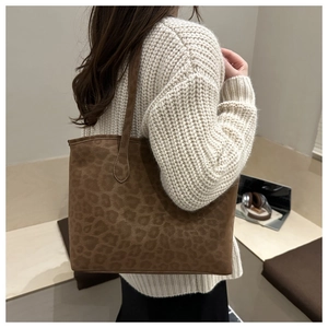 Detail of large leopard print tote bag with soft suede texture shown on shoulder