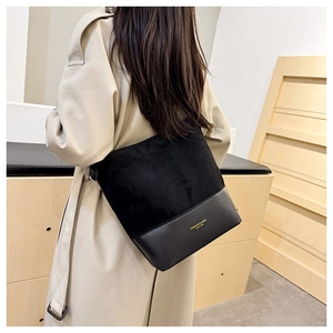 Details einer schwarzen Beuteltasche aus Wildleder am Model mit beigem Trenchcoat