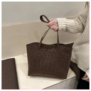 Detailed macro view of a dark brown leopard print suede tote bag with slim shoulder straps