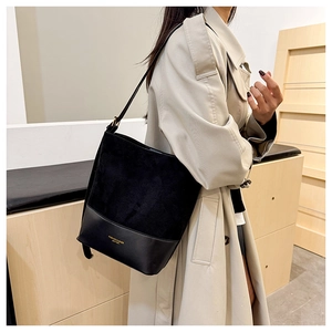 Detail of black suede and smooth leather bucket bag with golden fashion lettering