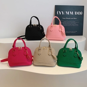 Retro shell bags in five colors with snake pattern and gold hardware on a display stand