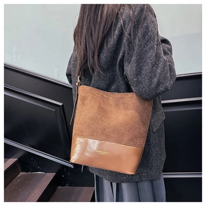 Makrodetail aus braunem Wildleder und Leder mit Goldbeschriftung auf einer Bucket Bag
