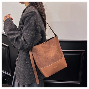 Detailaufnahme der braunen Wildleder-Patchwork-Tasche mit modischem Schriftzug und Gurt
