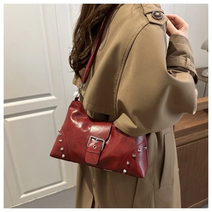 Detail of red vintage underarm bag with silver studs and metal buckle on trench coat
