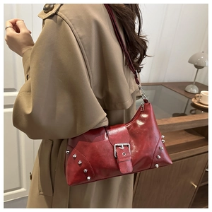 Detail view of deep red glossy faux leather shoulder bag with silver metallic rivets