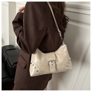 Detail of cream glossy leather tote bag with silver studs and metal buckle strap