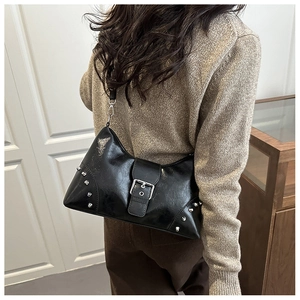 Detail of black crossbody bag with silver rivets and buckle on a shoulder strap
