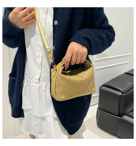 Detailed view of yellow woven PU leather texture and adjustable shoulder strap on the handbag