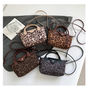 Detailed flat lay of four leopard print nylon handbags in various colors with leather handles