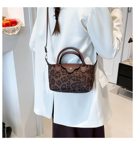 Detailed view of leopard print nylon handbag with brown leather accents on a white blazer