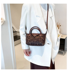 Detail of leopard print nylon bag with leather flap and metal snap on white blazer