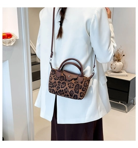Detail of leopard print handbag with brown leather handles and magnetic snap closure