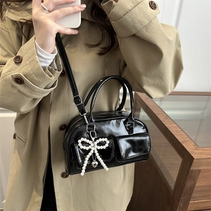 Glossy black bowling bag with oversized pearl bow charm and silver heart detail