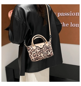 Detail of leopard print canvas bag with beige leather handle and snap closure flap