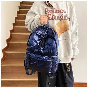 Detail of blue quilted puffer backpack with glossy finish and zippered front pocket