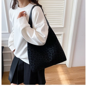 Fashionable leopard print oversized tote bag in black suede styled on a model's shoulder