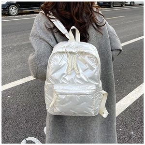 Outdoor shot of a white quilted metallic backpack on a model in a grey winter coat
