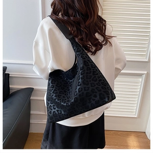 Detail of large black hobo tote bag with subtle leopard texture on shoulder