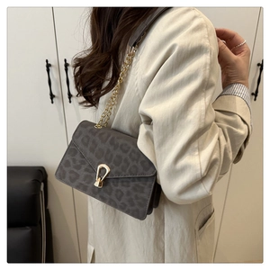 Close-up of leopard print shoulder bag with golden horseshoe buckle and chain strap