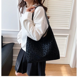 Close-up of black leopard print bucket bag with suede texture on white sweatshirt