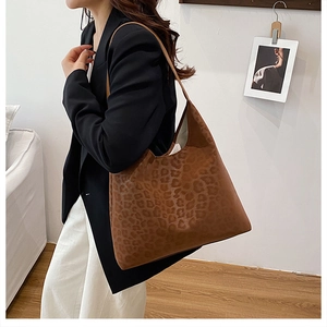 Side view of a vintage leopard print tote bag worn on shoulder in a minimalist setting