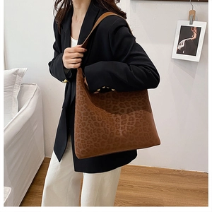 Detailed view of large leopard print tote bag with brown leather straps on model