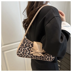 Détail du sac baguette léopard avec nœud en cuir verni beige et bandoulière sur l'épaule