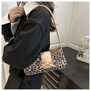 Detailed side view of leopard print crescent bag with khaki bow on a shoulder strap